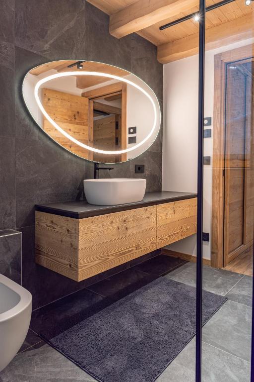 Mobile lavabo in legno con specchio retroilluminato in un bagno finito.