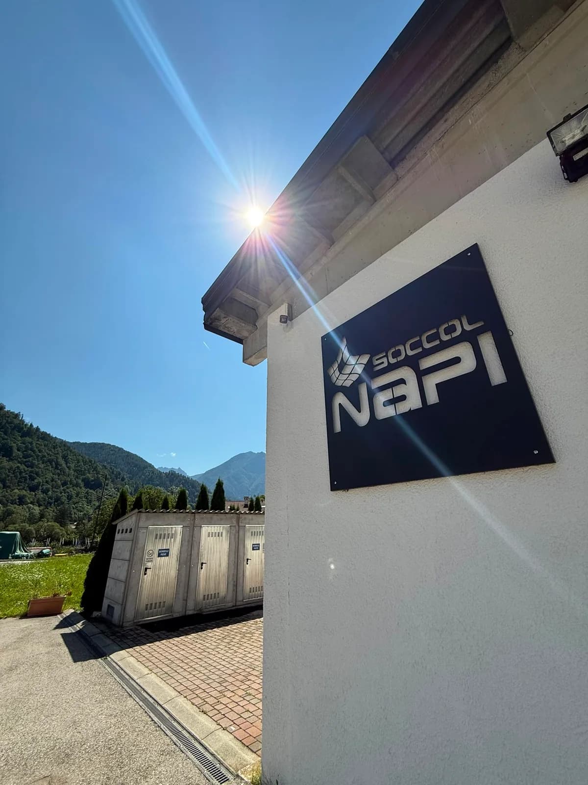 Insegna Soccol Napi sull’edificio, con il sole e le montagne sullo sfondo